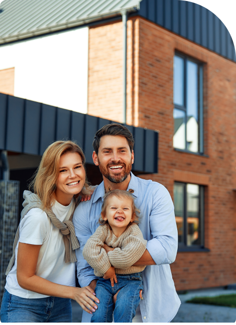 Glückliche Familie vor einem modernen Backsteinhaus – Symbolbild für Baufinanzierung und Eigenheimplanung.