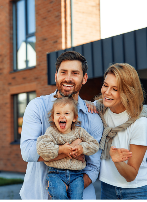 Glückliche Familie vor einem modernen Backsteinhaus – Symbolbild für Baufinanzierung und Eigenheimplanung.